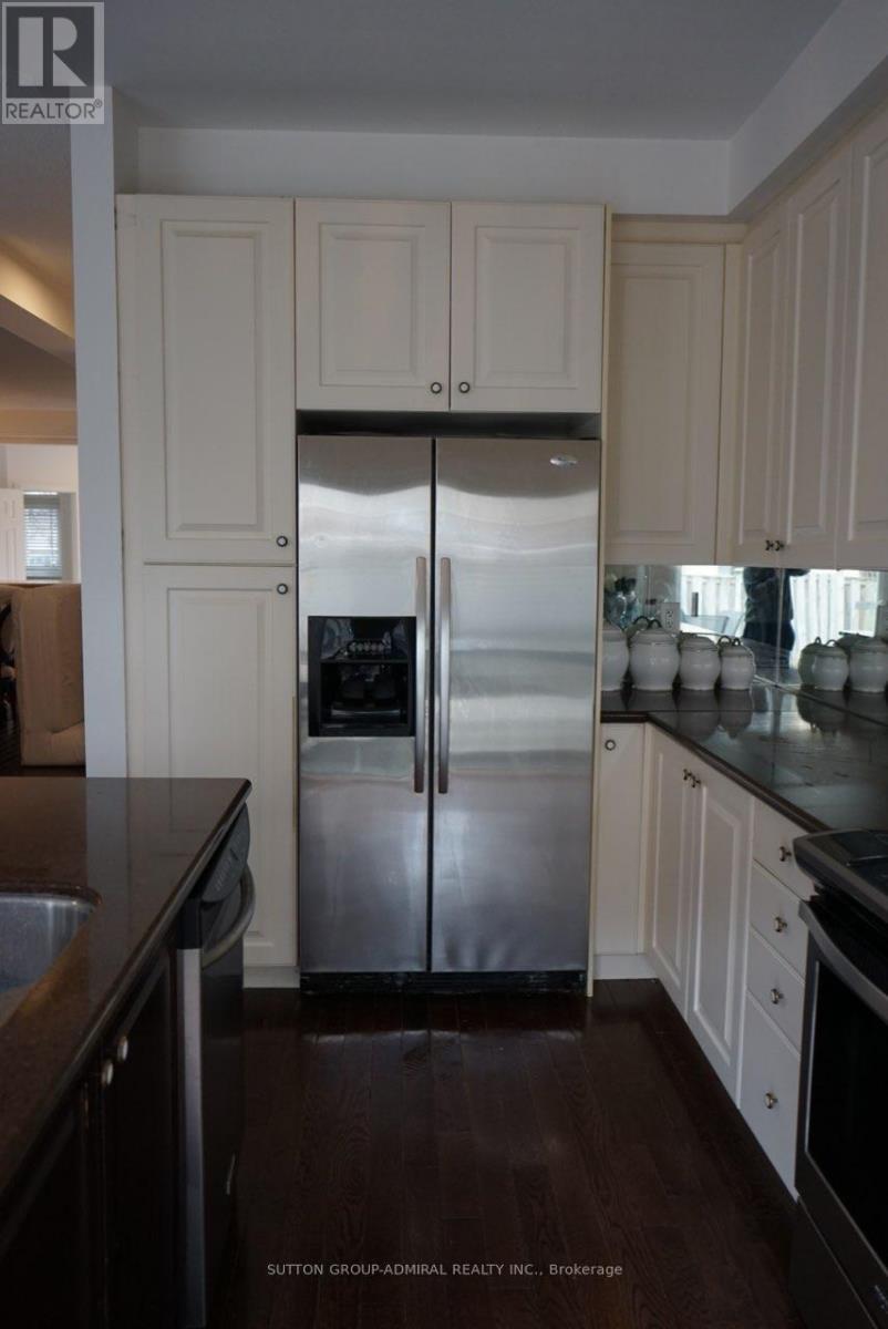 A kitchen with a stainless steel refrigerator and wooden floors.