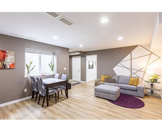 A modern living room with a grey sofa and a dining table with chairs.