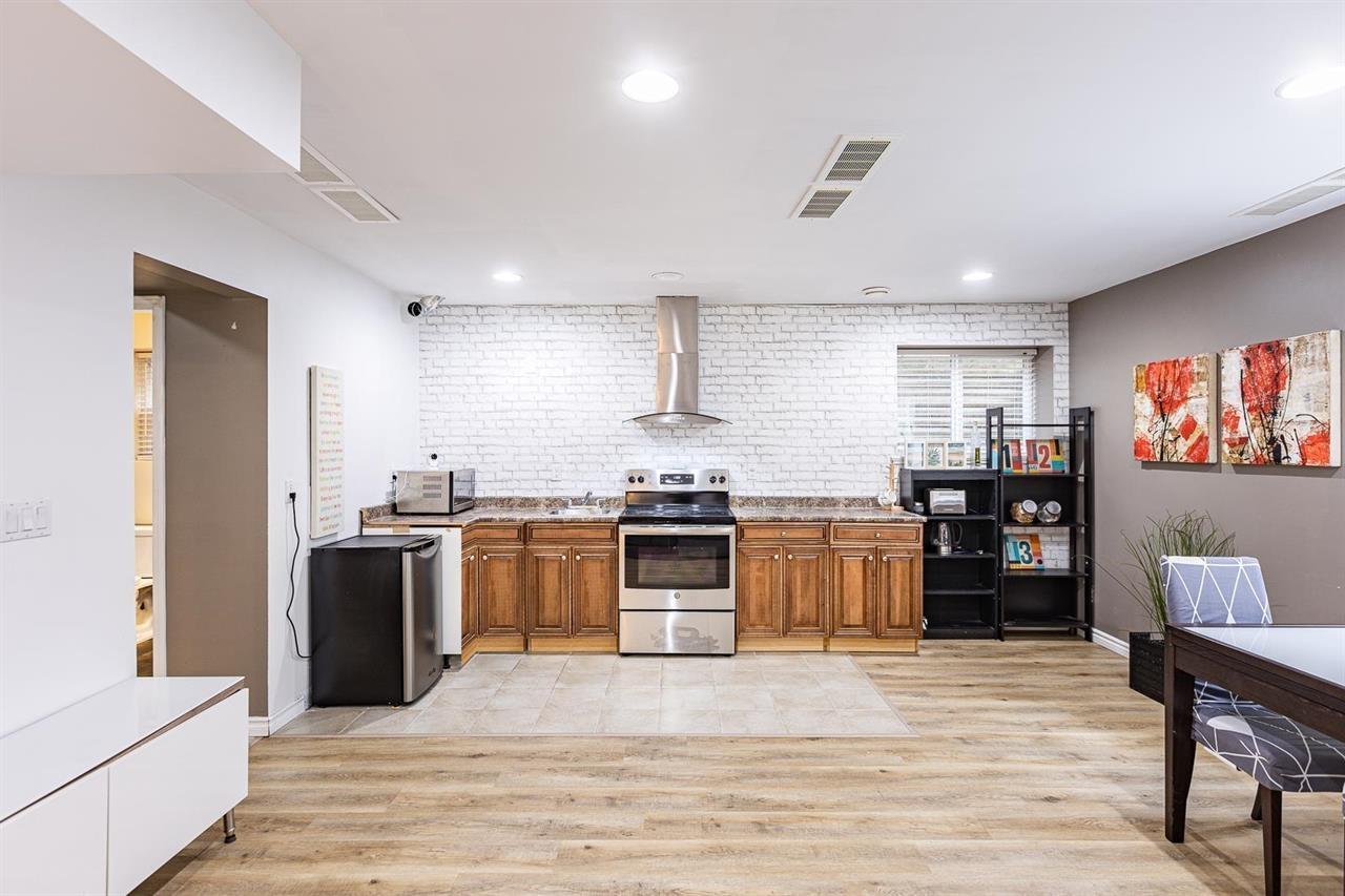 A modern kitchen with wooden floors and a white brick backsplash.