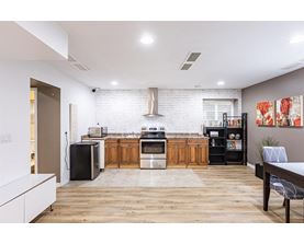 A modern kitchen with wooden floors and a white brick backsplash.