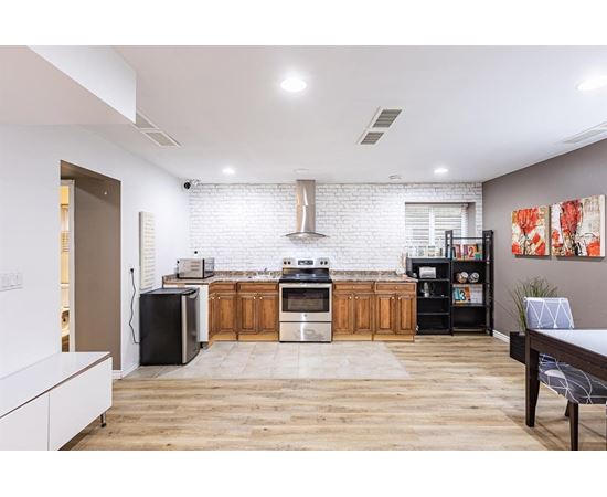 A modern kitchen with wooden floors and a white brick backsplash.