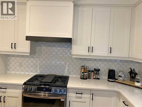 A kitchen with white cabinets and a black stove top.
