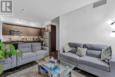 A living room with a grey couch and a glass coffee table.