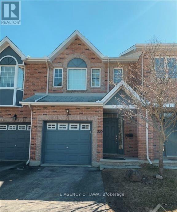 A brick house with a black garage door is for sale.