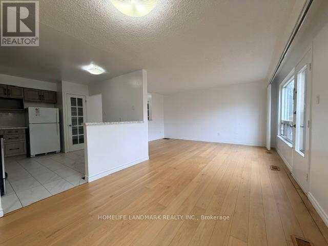 A large empty room with wooden flooring and white walls.