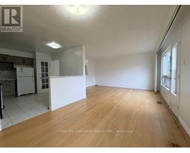A large empty room with wooden flooring and white walls.