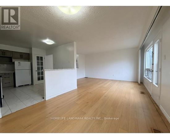 A large empty room with wooden flooring and white walls.