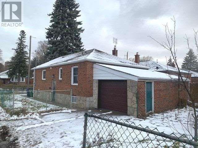 A house with a red garage door is surrounded by a chain link fence.
