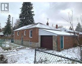 A house with a red garage door is surrounded by a chain link fence.