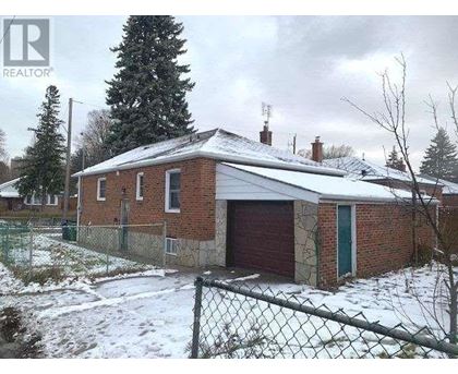 A house with a red garage door is surrounded by a chain link fence.