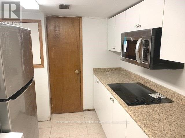 A kitchen with a refrigerator, microwave, and oven.