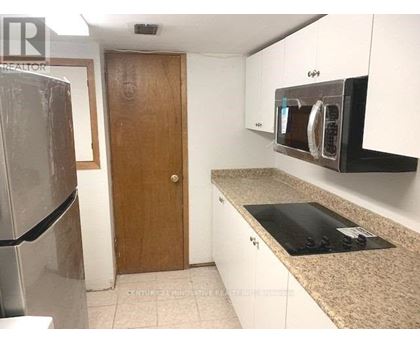 A kitchen with a refrigerator, microwave, and oven.