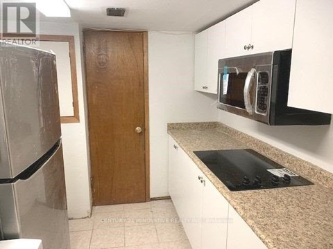 A kitchen with a refrigerator, microwave, and oven.