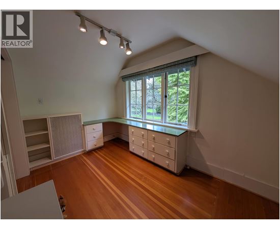 A room with wooden floors and a window with a view of trees.