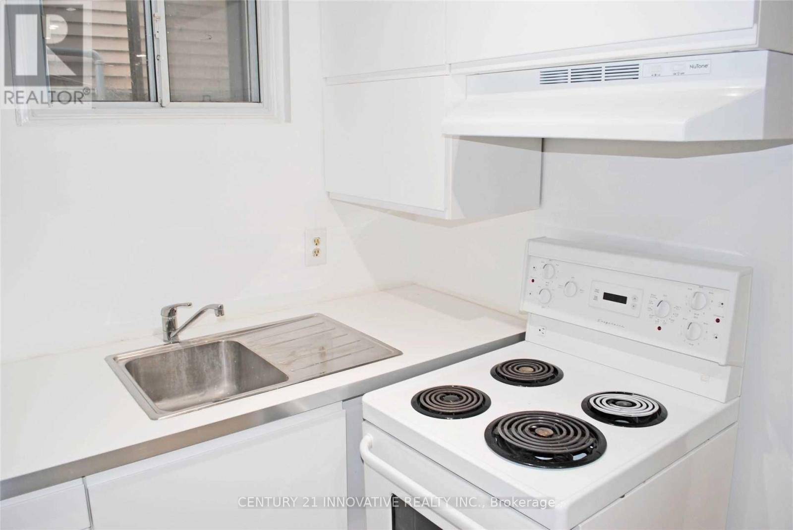 A white stove with a silver sink in a kitchen.