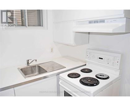 A white stove with a silver sink in a kitchen.