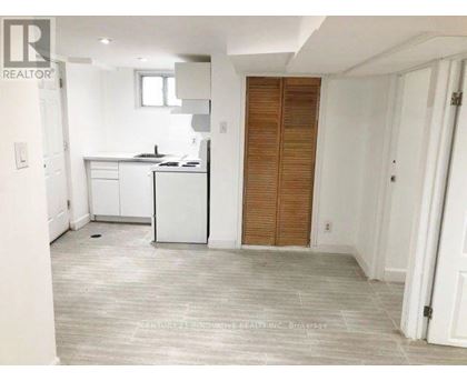 A realtor photo of a kitchen with white cabinets and a wooden door.