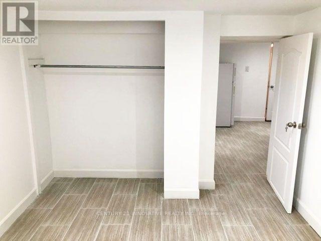 A white bedroom with a large bed and a doorway leading to another room.