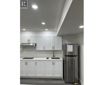 A kitchen with white cabinets and a stainless steel refrigerator.