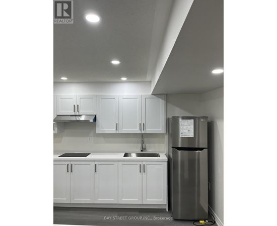 A kitchen with white cabinets and a stainless steel refrigerator.