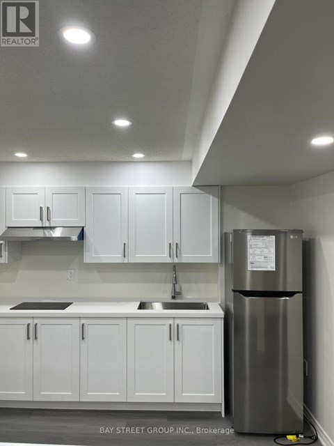 A kitchen with white cabinets and a stainless steel refrigerator.