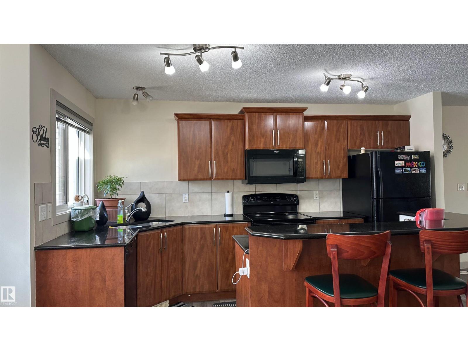 A kitchen with wooden cabinets and black appliances.