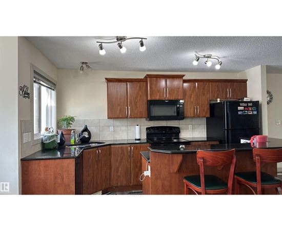 A kitchen with wooden cabinets and black appliances.