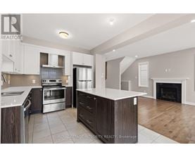 A modern kitchen with a stainless steel refrigerator, oven, and a fireplace in the living room.