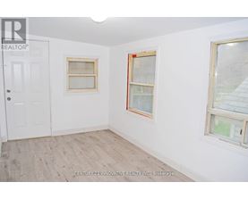 A room with a white door and two windows with wooden frames.