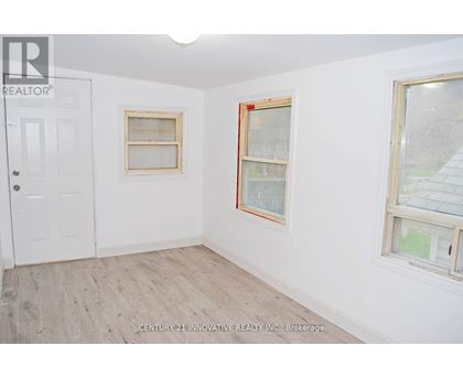 A room with a white door and two windows with wooden frames.