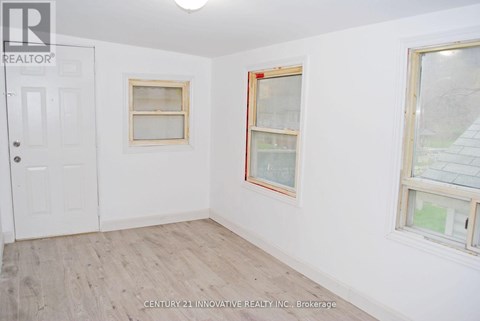 A room with a white door and two windows with wooden frames.