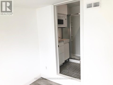 A white refrigerator is in a kitchen with a white wall.