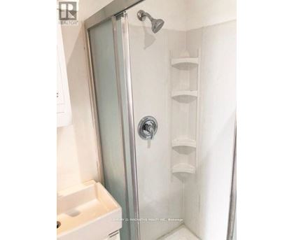 A shower with a glass door and a white sink.