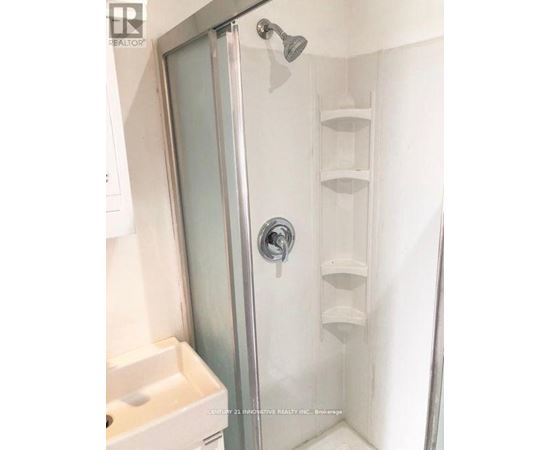 A shower with a glass door and a white sink.