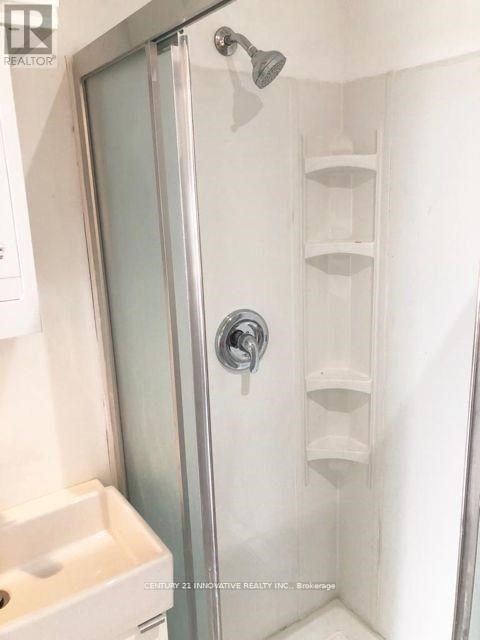 A shower with a glass door and a white sink.
