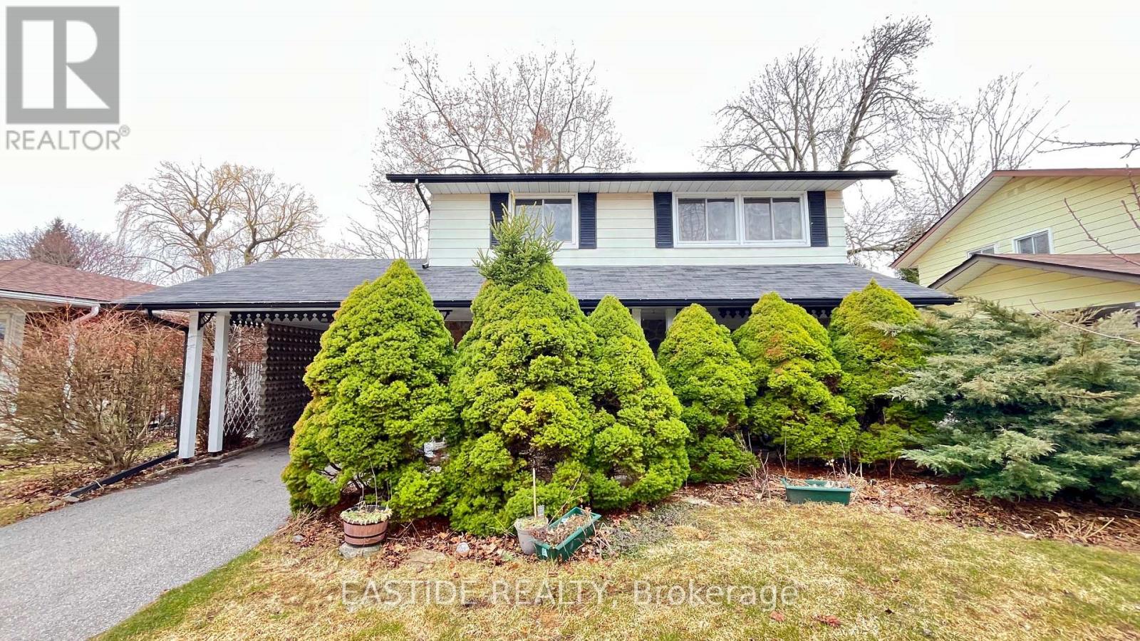 A house with a white and black exterior is surrounded by green shrubbery.