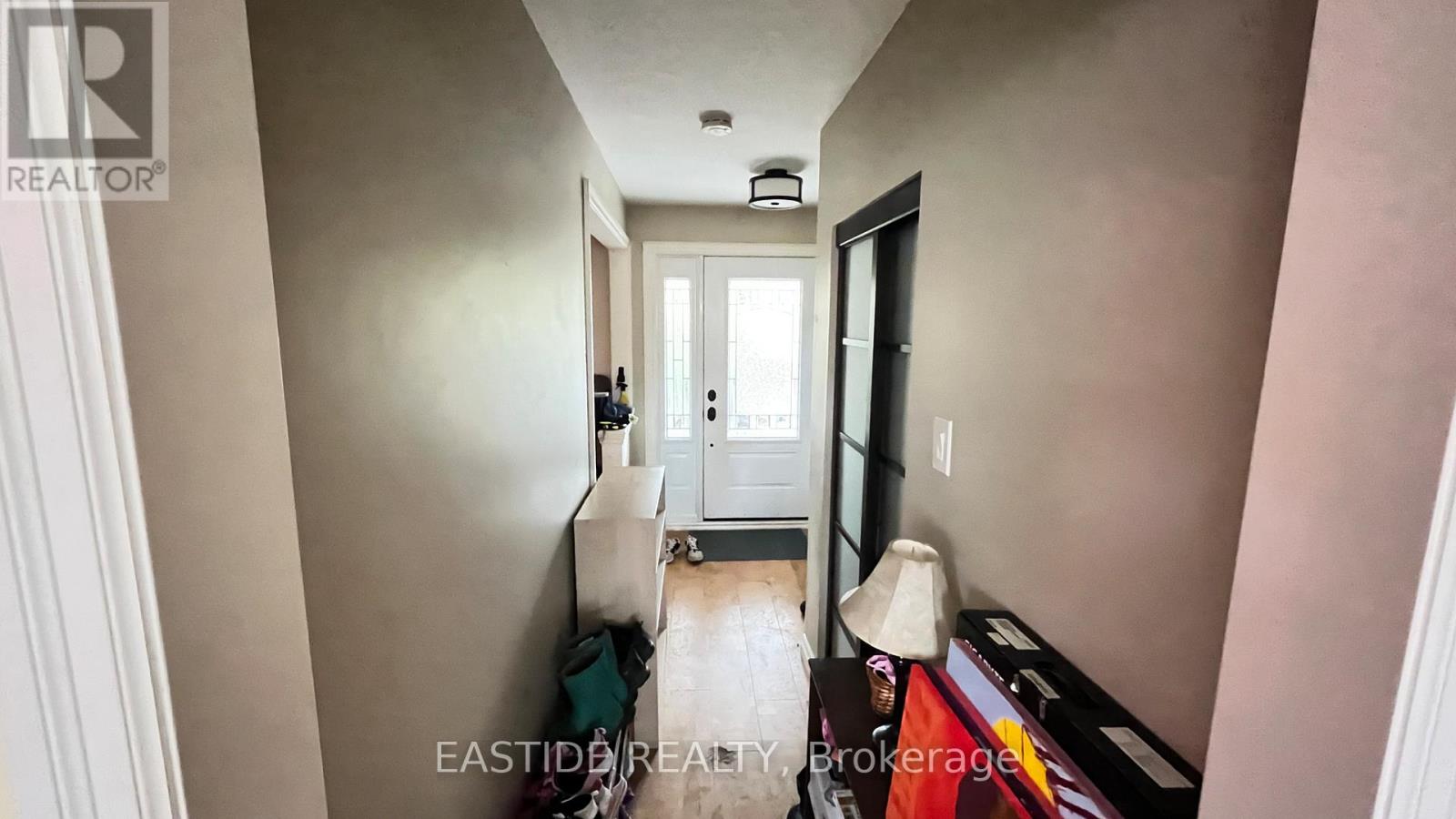 A hallway with a door at the end and a bed on the right side.
