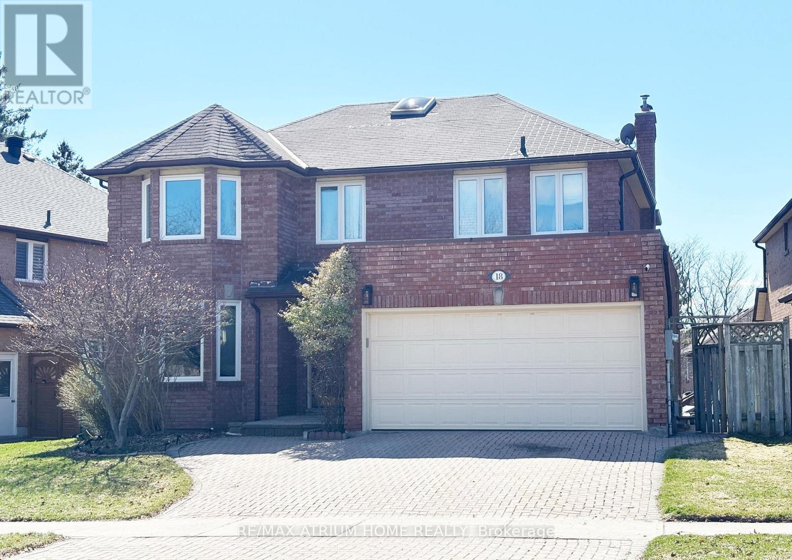 A large brick house with a white garage door in the front yard.