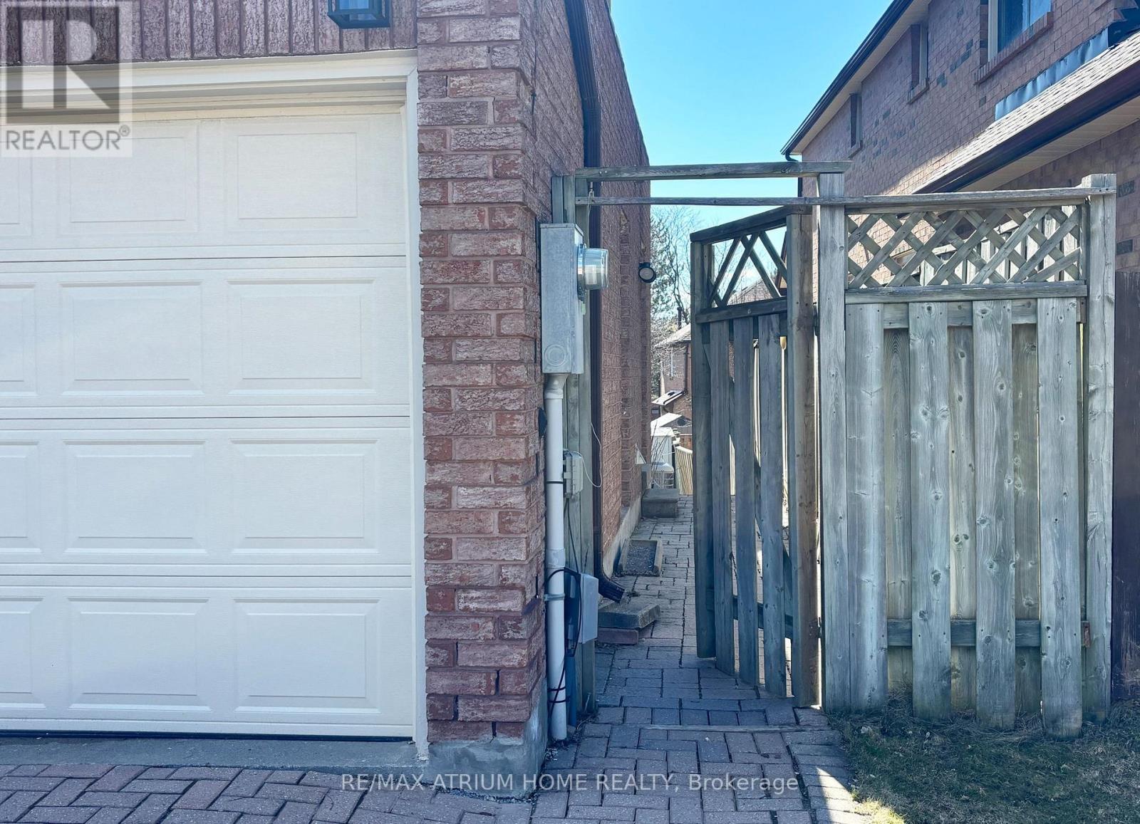 A white garage door is closed and a wooden gate is open.
