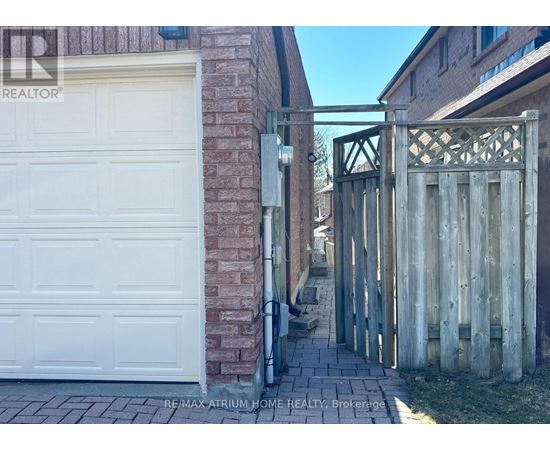 A white garage door is closed and a wooden gate is open.