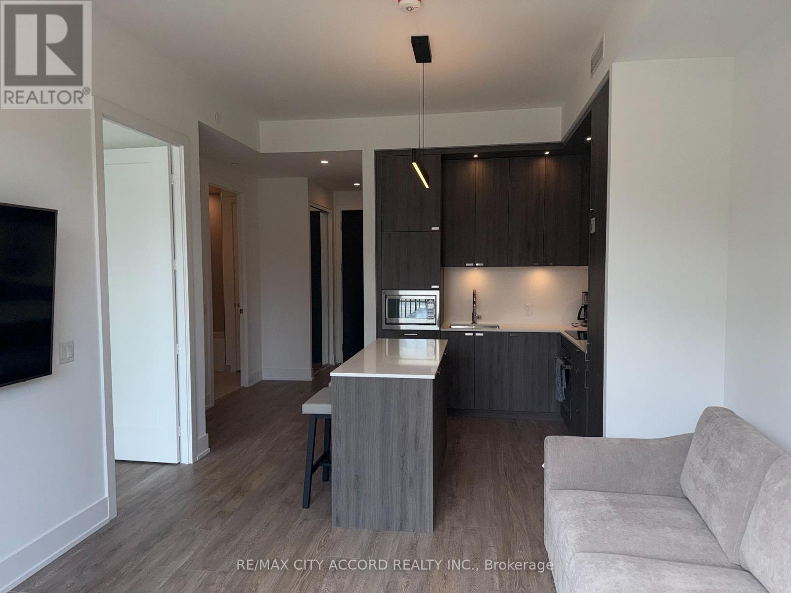 A modern kitchen with dark brown cabinets and a white island.