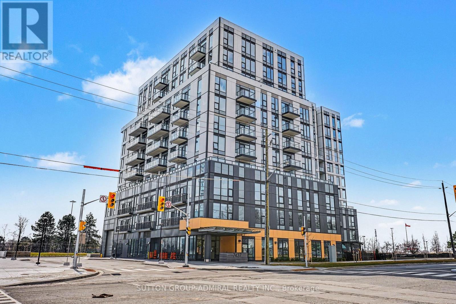 A modern multi-story building with a glass facade and a yellow entrance.