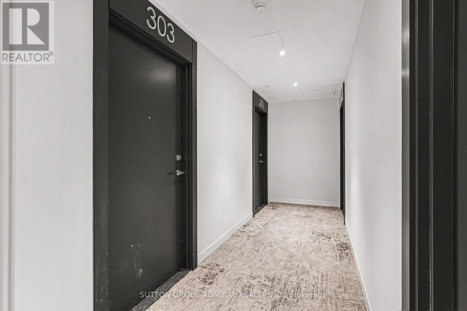 A hallway with a black door and a carpeted floor.