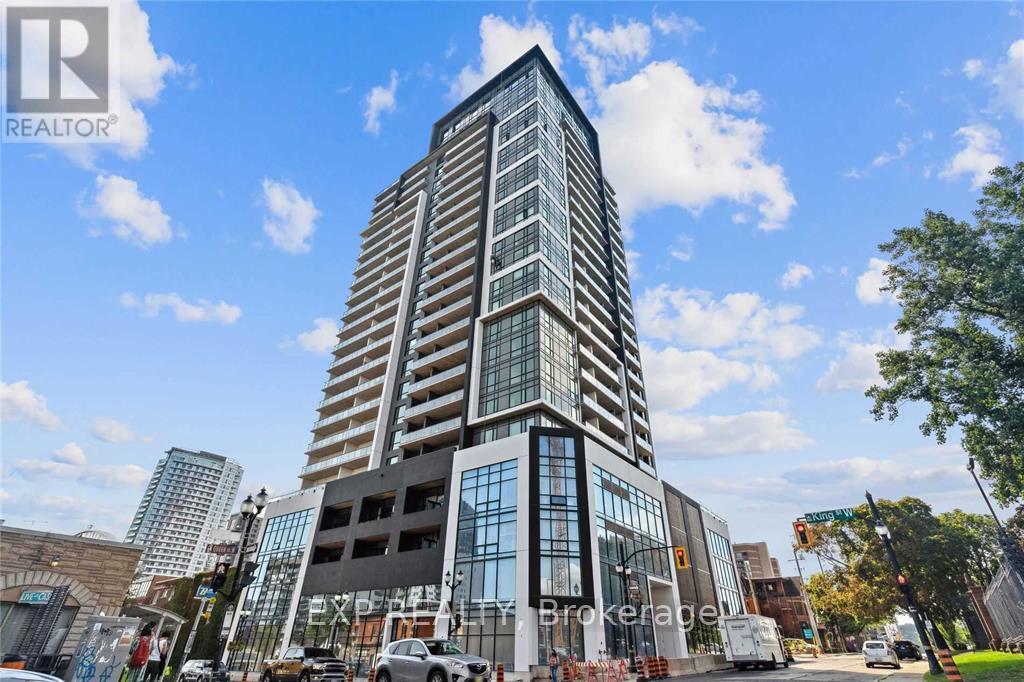 A tall building with a glass facade stands in the middle of a city street.