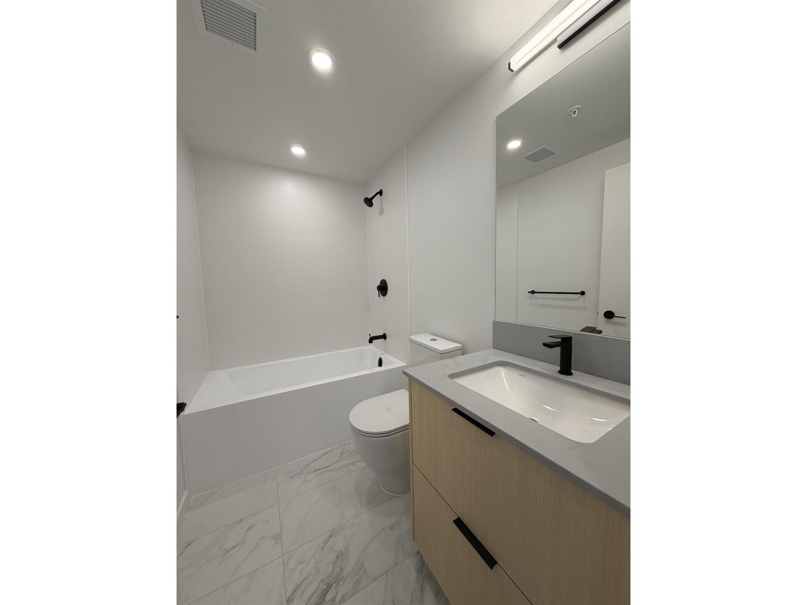 A white bathroom with a tub, toilet, and sink.