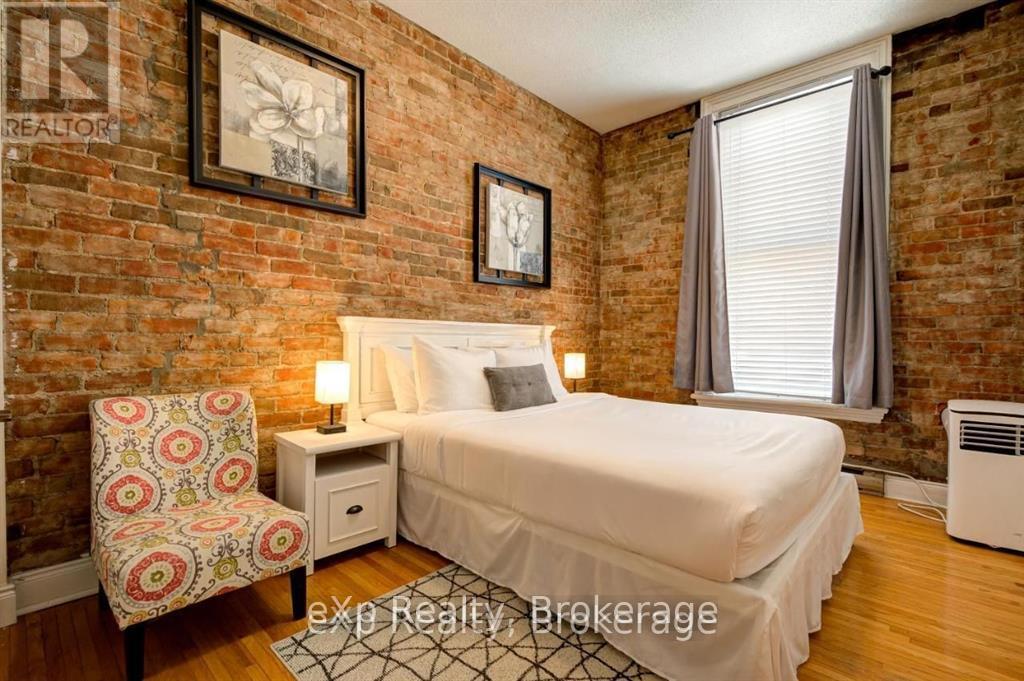 A bedroom with a brick wall and a bed with white bedding.