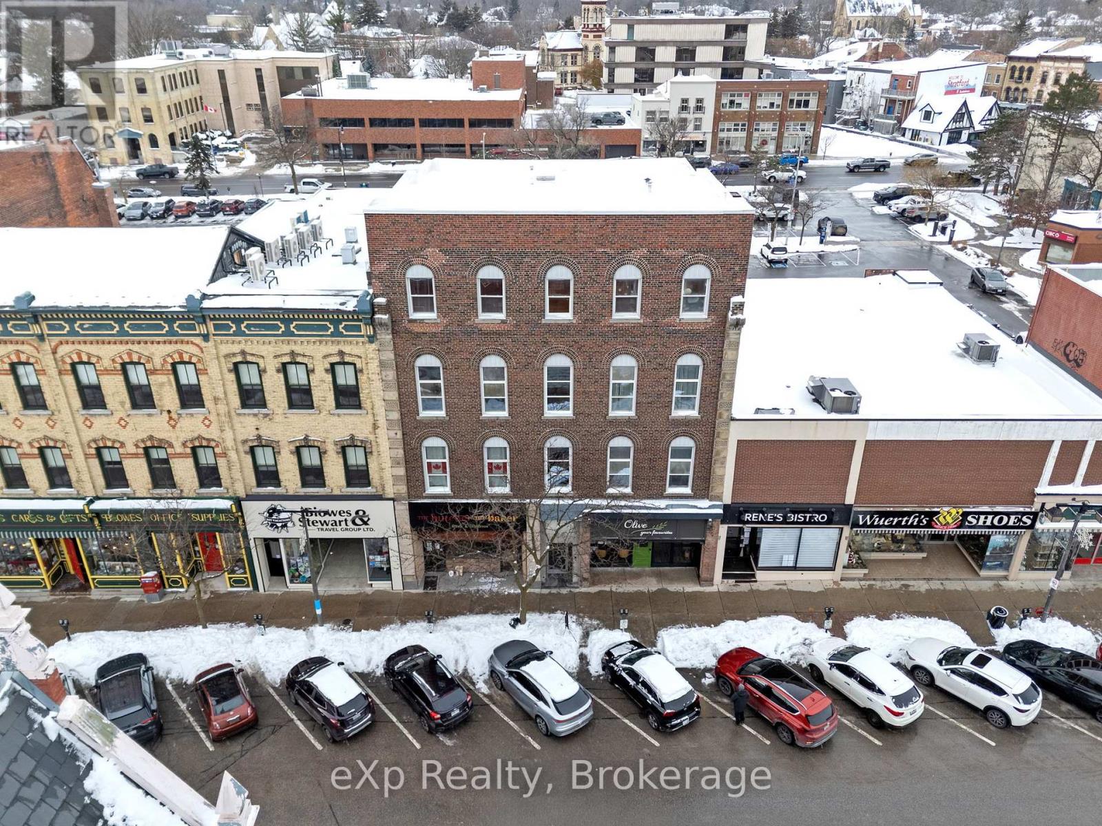 A parking lot with cars and a building with a sign that says "eXp Realty, Brokerage".