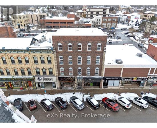 A parking lot with cars and a building with a sign that says "eXp Realty, Brokerage".