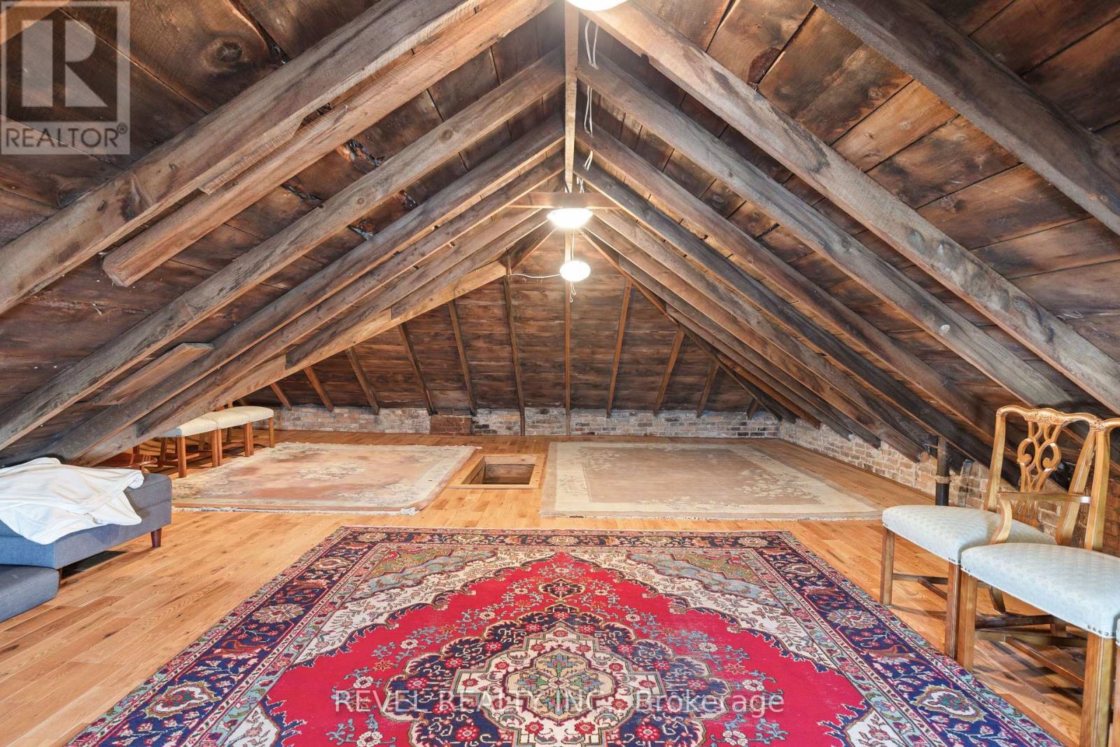 A large, open attic space with wooden beams and a rug on the floor.