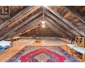 A large, open attic space with wooden beams and a rug on the floor.